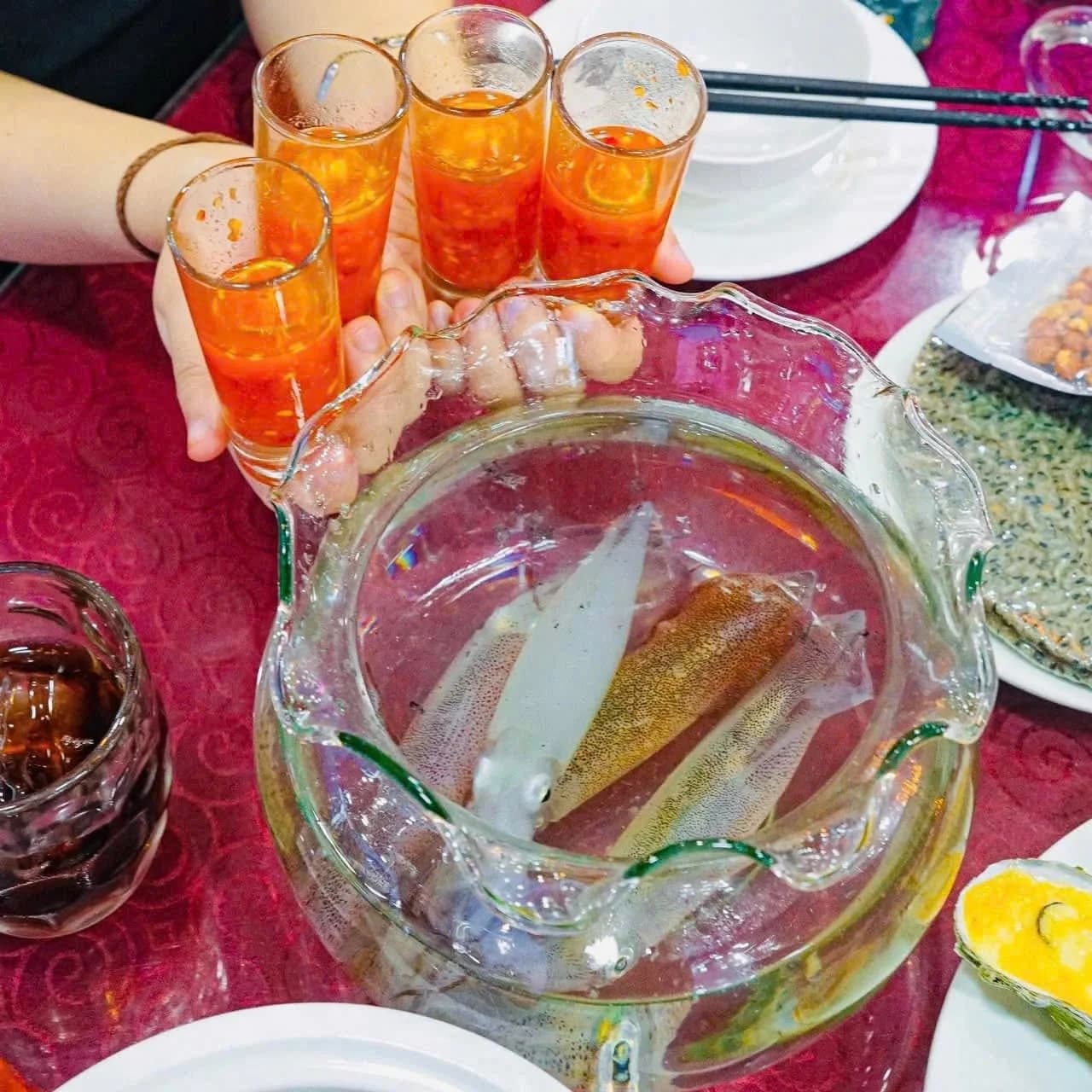 Nhân viên vớt mực nhảy tươi sống trong bể nuôi nước biển tuần hoàn tại nhà hàng hải sản Đại Hương Biển